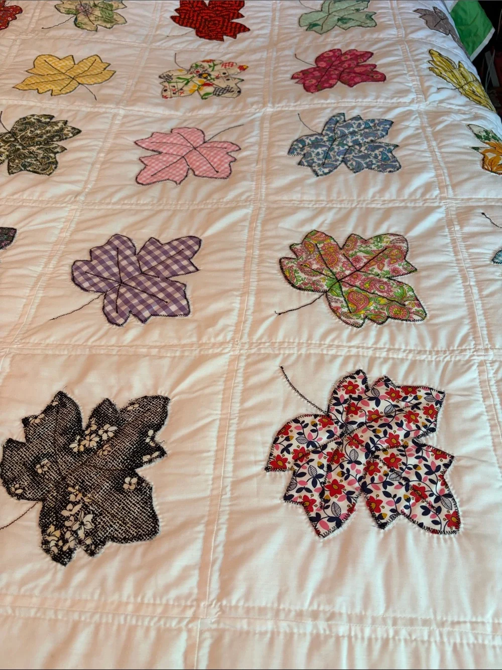 Vintage quilt handcrafted with color leaf blocks on white with green trim